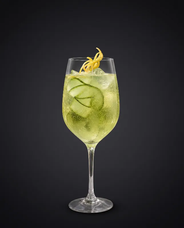 Waldmeister-Spritz im Weinglas in frischem Grün mit Eis und Zitronenzeste